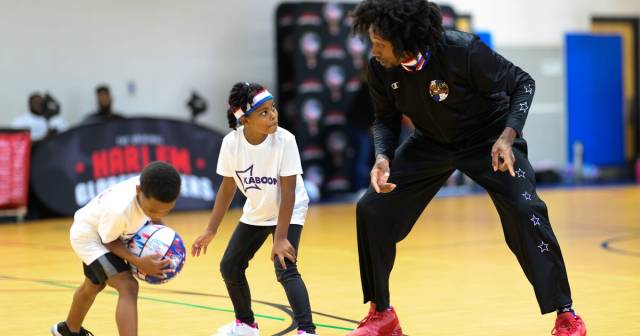 A Globetrotter teaches basketball pointers to kids.
